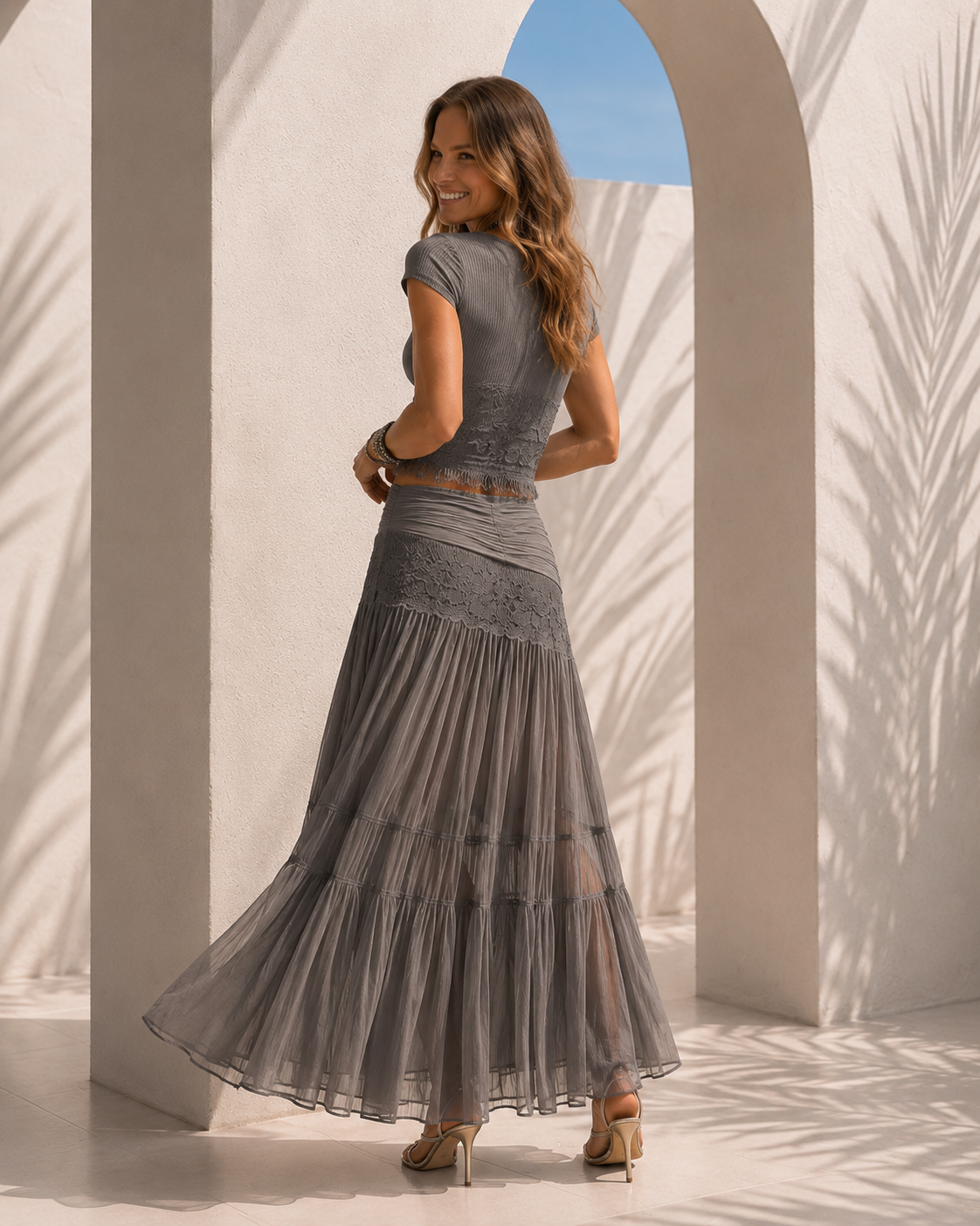 Conjunto compuesto por un top gris con paneles de encaje y una falda larga plisada